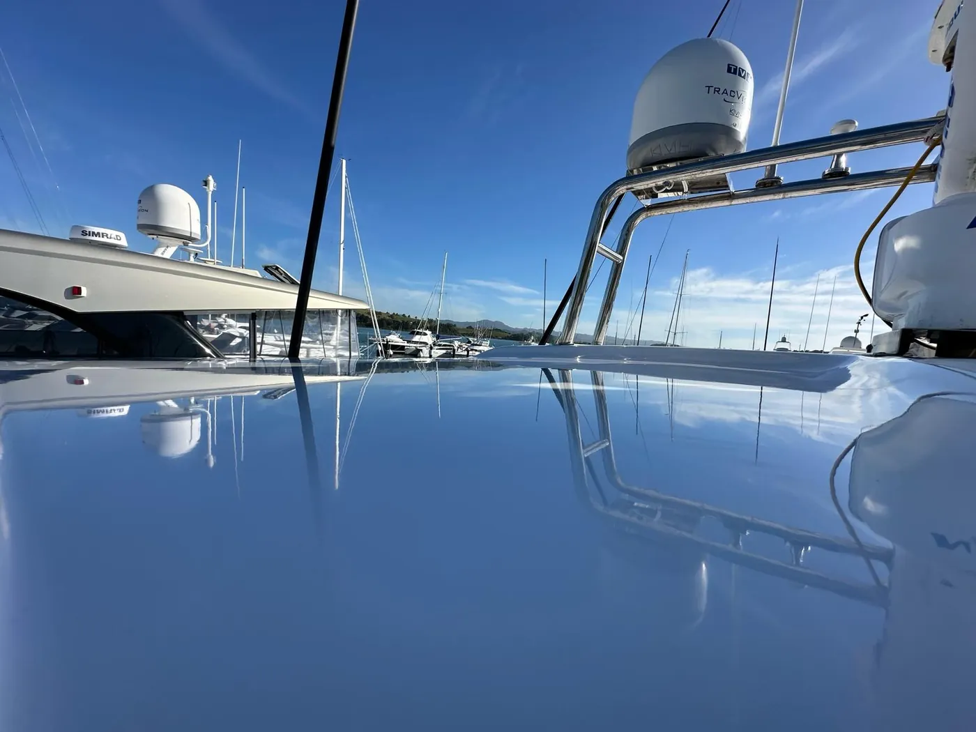 Boat rooftop cut back to a deep gloss, reflecting the marina and sky — Warkworth