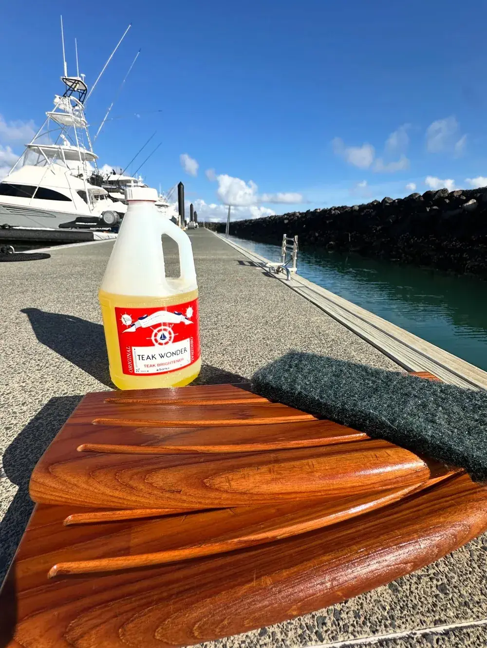 Teak deck deep-scrubbed and brightened during boat detailing, marina in background